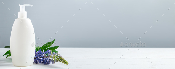 Cosmetic bottle with lotion and lupine flowers on gray background. - Stock Photo - Images