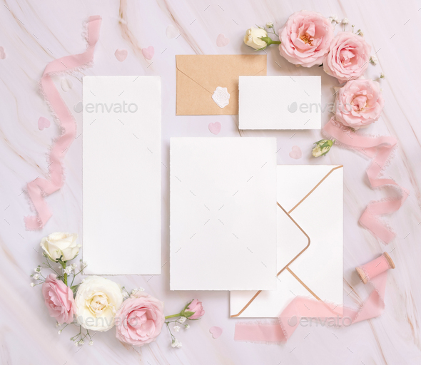 Cards and envelope between pink roses and pink silk ribbons on marble top view, wedding mockup - Stock Photo - Images