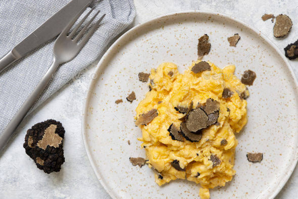 Scrambled eggs with fresh black truffles from Italy served in a plate top view, gourmet breakfast - Stock Photo - Images