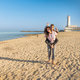 Happy Mother and son running on beach barefoot in a sunny day against the lighthouse - PhotoDune Item for Sale
