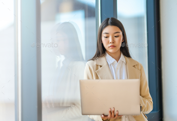 woman is using laptop standing near the window - Stock Photo - Images