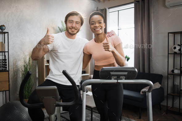 Young couple doing cardio on stationary bike and treadmill.