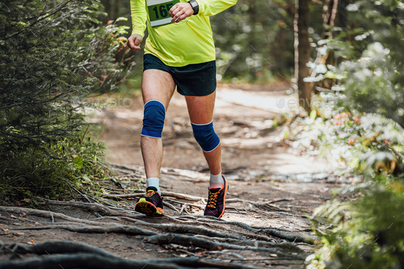male athlete runner in knee pads run forest trail race