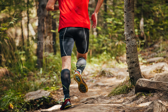 male runner in compression calf sleeve running forest trail Stock Photo by  realsportsphotos