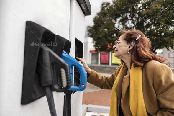 mature woman charging electric car - Stock Photo - Images