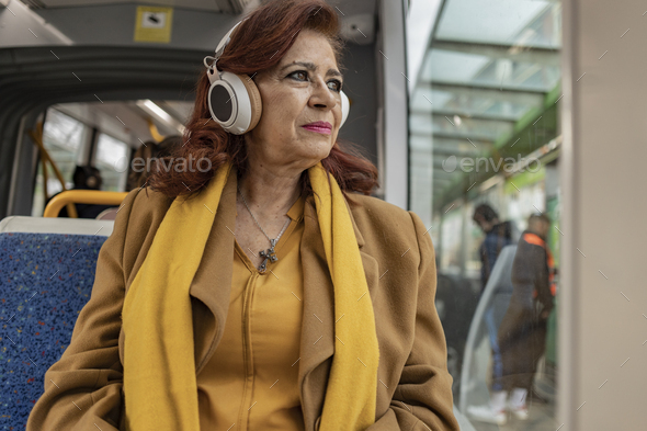 senior woman on the train on the way home. listen to music with headphones, look out the window - Stock Photo - Images
