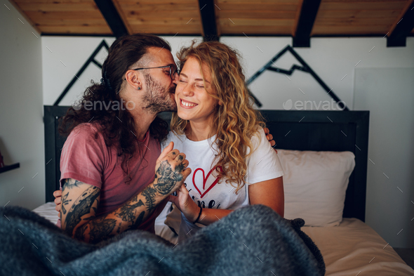Romantic couple lying in the bed at home in the morning and kissing - Stock Photo - Images