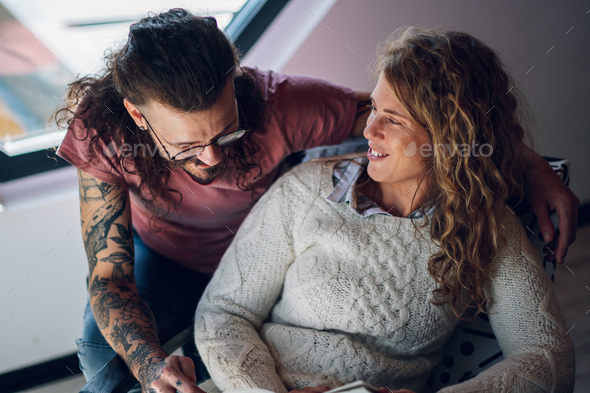Couple spending time together at home while reading a book and hugging - Stock Photo - Images