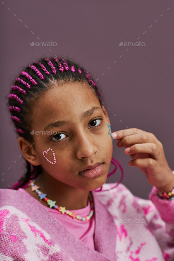 Close up black teenage girl with sparkling tattoos on face looking at camera - Stock Photo - Images