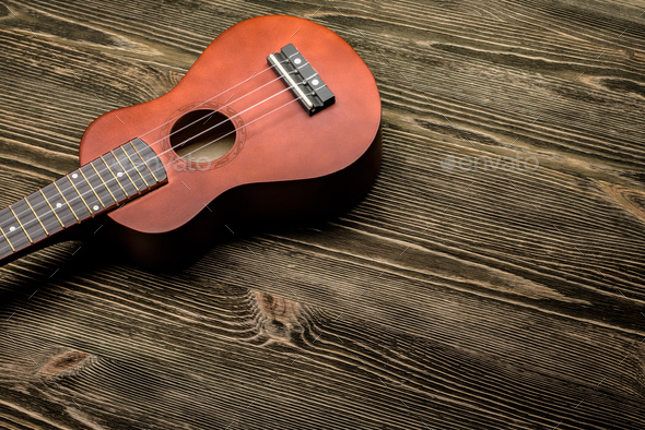 Hawaiian ukulele guitar on brown wooden background. - Stock Photo - Images