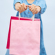 Pretty child girl in casual denim dress hold in hand pink shopping bags - PhotoDune Item for Sale