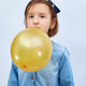 Pretty little girl in casual denim dress blowing, inflate yellow balloon - PhotoDune Item for Sale
