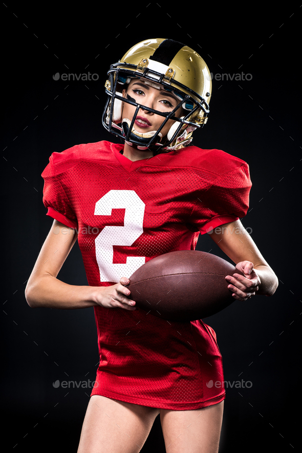 Attractive female american football player in uniform posing with