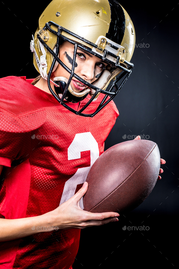 Attractive female american football player in uniform posing with