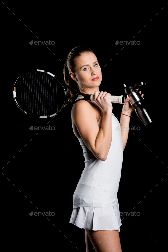 Attractive female tennis player holding sport bottle and tennis racquet isolated on black Stock