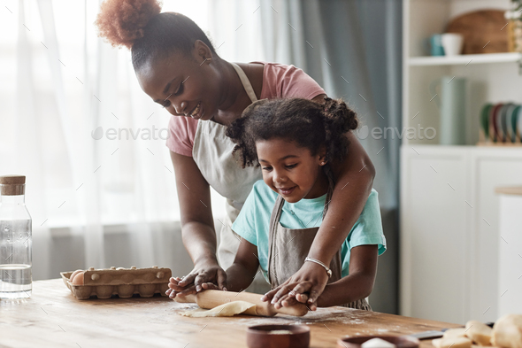 Candid loving mother and daughter baking together at home - Stock Photo - Images