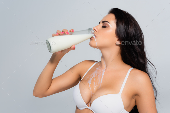sexy woman in bra holding bottle and drinking milk isolated on grey Stock  Photo by LightFieldStudios