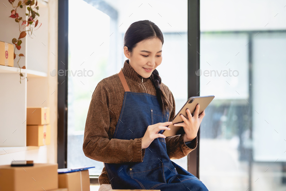 Beautiful young Asian business woman owner selling online using tablet to chat with customer.
