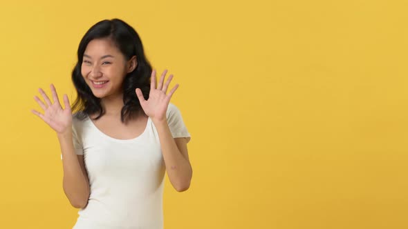Cute happy smiling Asian woman in white t-shirt waving and dancing left and right