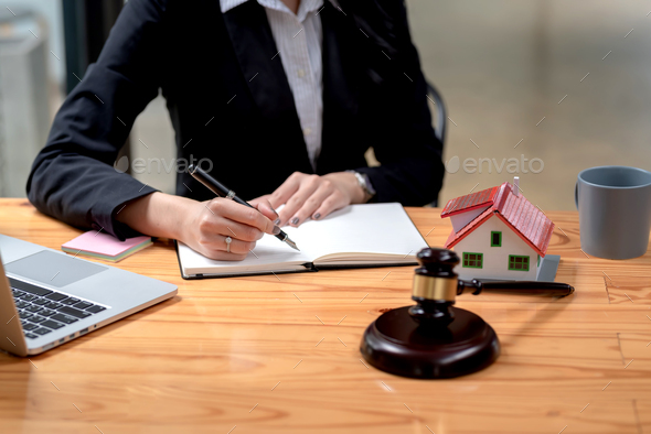 Close-up of a woman lawyer holding a pen and taking notes on a sample house mallet placed at the off