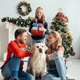 joyful parents in sweaters cuddling labrador near daughter with presents and decorated christmas - PhotoDune Item for Sale