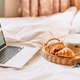 Wicker tray with croissants and coffee on white bed linen with laptop - PhotoDune Item for Sale