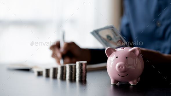 A pink piggy bank and a pile of coins are placed. Money saving. - Stock Photo - Images