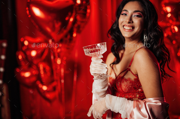 Portrait of happy smiling sexy asian girl glam makeup in red lingerie with coupe champagne glass - Stock Photo - Images