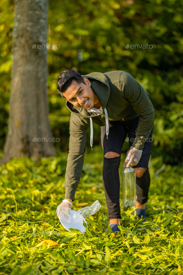 Dedicated volunteer cleaning garbage on grass in nature - Stock Photo - Images