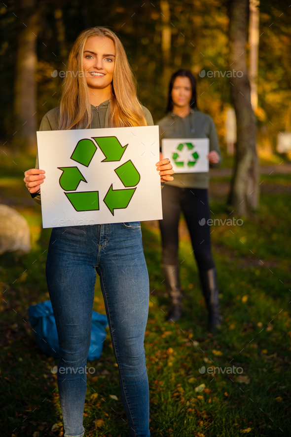 Smiling woman holding recycling symbol placard togheter with her team - Stock Photo - Images