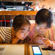 Two young children using smartphone while their food arrive at a restaurant - PhotoDune Item for Sale
