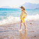 Little girl walking on beach, sea ocean shore in romantic yellow dress, straw hat. Playing in  - PhotoDune Item for Sale