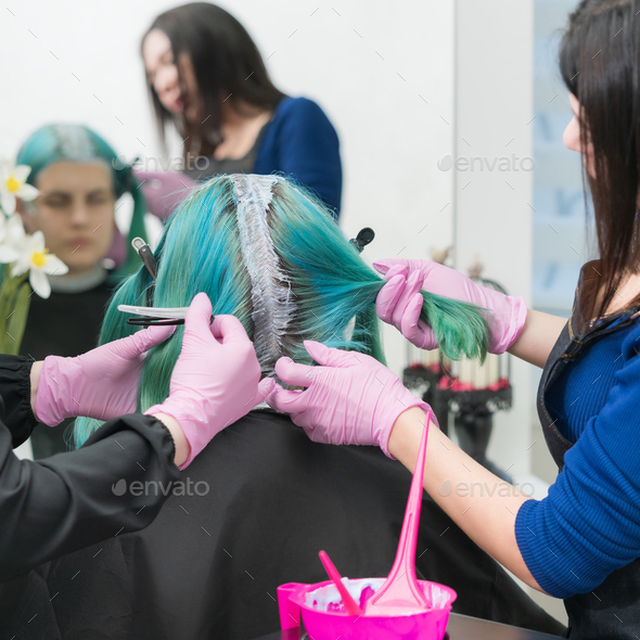 Process hair dyeing in beauty salon. Hairdressers applying paint to hair during bleaching hair roots