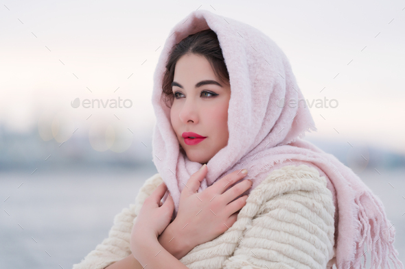 Portrait of charming young woman on frosty winter evening outdoors looking away, hugging self - Stock Photo - Images