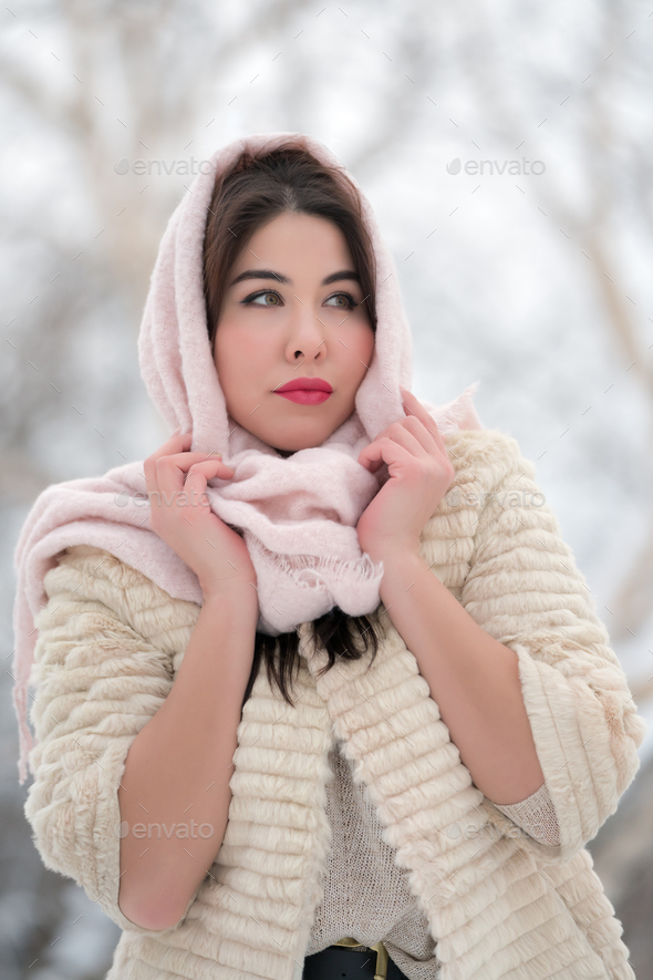 Charming brunette young woman dressed in white three-quarter sleeve fur coat and pink scarf on head - Stock Photo - Images