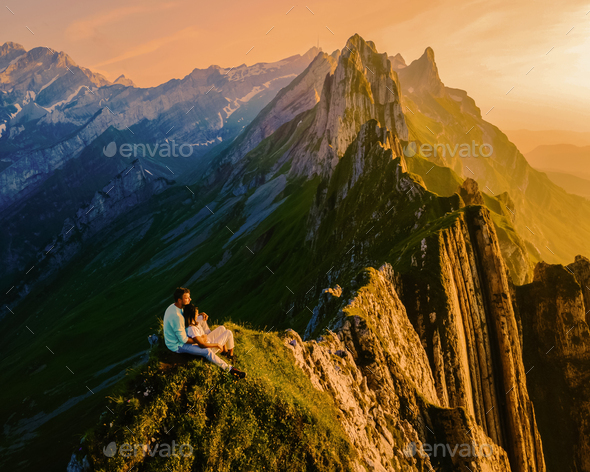 Couple watching sunset at the mountains Schaefler Altenalptuerme mountain ridge swiss Alpstein  - Stock Photo - Images