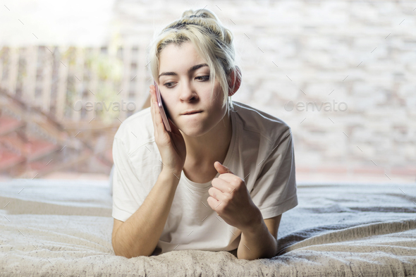 Relaxed woman using a smart phone in the morning on the bed at home - Stock Photo - Images