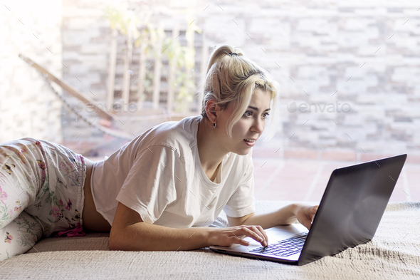 Serious woman working at home behind laptop in the morning - Stock Photo - Images