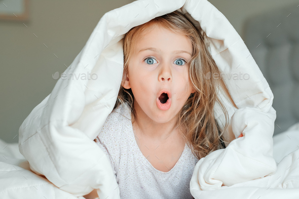 surprised emotion happy excited child adorable girl white cotton fluffy blanket children emotions