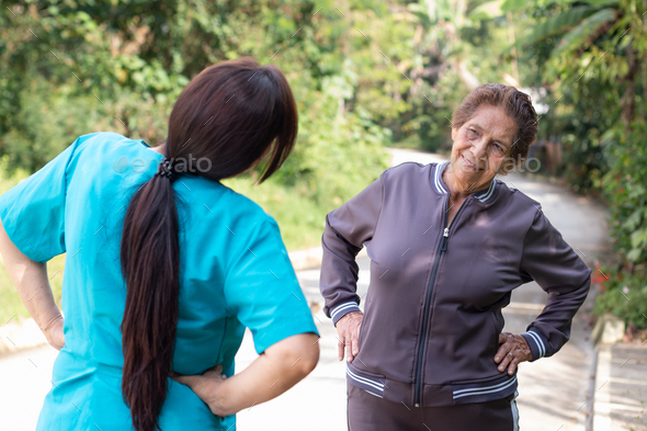 A nurse guides an elderly woman in hip stretching exercises to improve mobility and health.