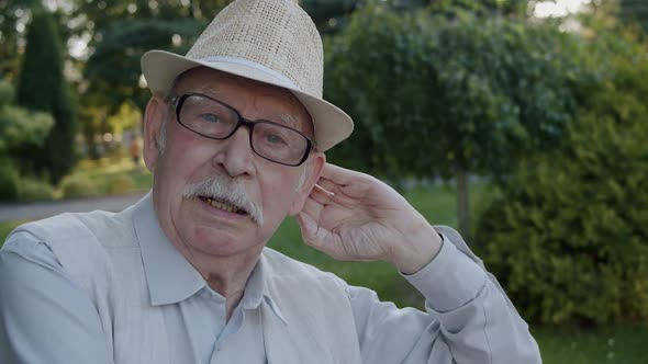 Senior Man with Glasses in Hat and Suit Tells Poetically Confidently to Camera alt