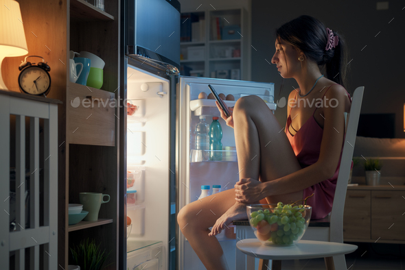 Woman cooling herself in front of the open fridge