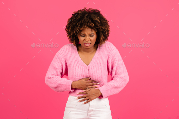 Sad pretty young black curly woman in casual suffering from stomach hurt, menstrual pain