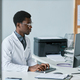 Young black doctor using computer at desk in office working in clinic - PhotoDune Item for Sale