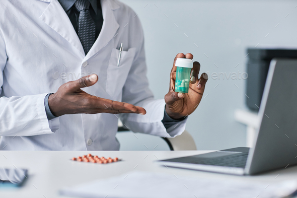 Close up black doctor holding bottle of pills during online consultation - Stock Photo - Images