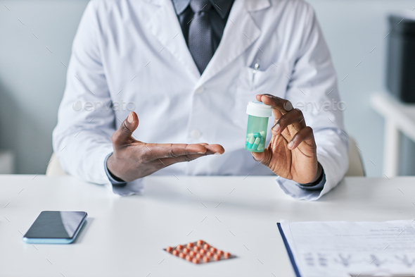 Closeup black doctor holding bottle of pills - Stock Photo - Images