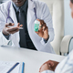 Close up black doctor holding bottle of pills consulting patient in clinic - PhotoDune Item for Sale
