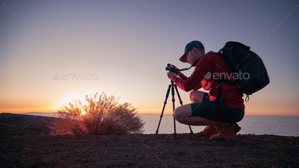 Photographer with camera on tripod at sunset - Stock Photo - Images