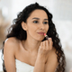 Glad pretty islamic millennial curly female in towel applying lipstick on lips, looking in mirror in - PhotoDune Item for Sale