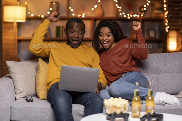 Emotional african american couple gambling on Internet - Stock Photo - Images